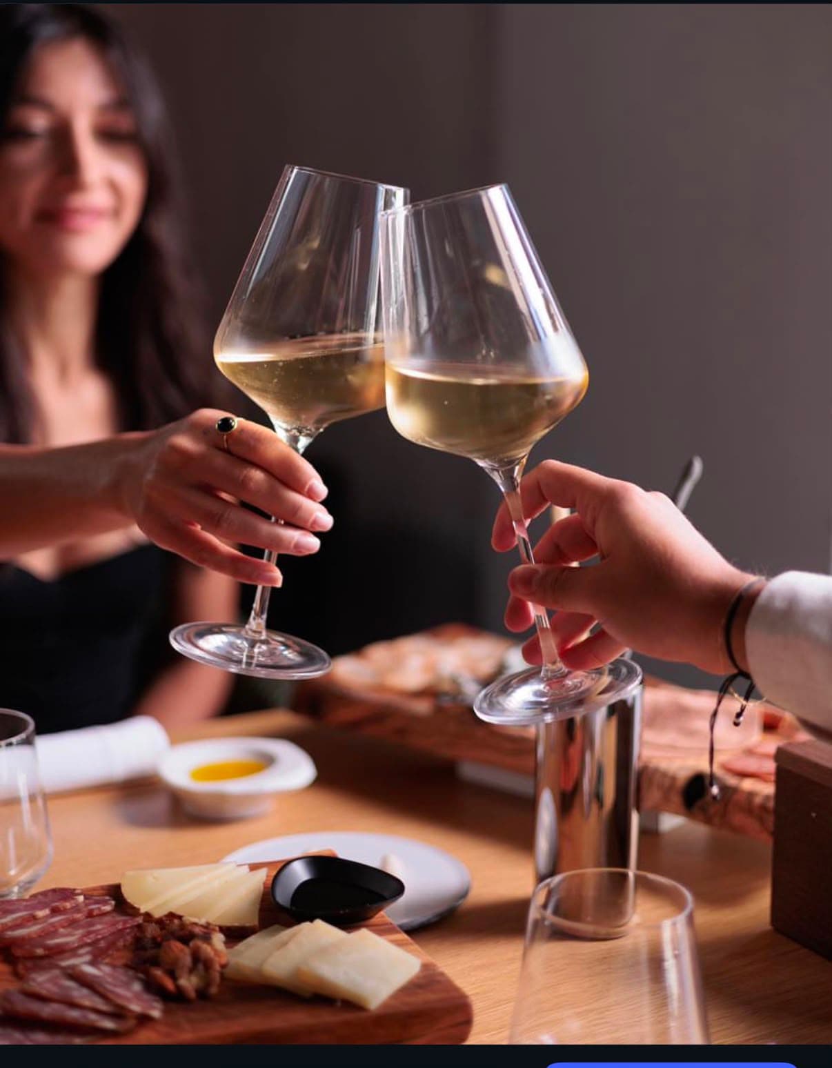 Brindisi al tavolo con tagliere e bicchieri di vino bianco